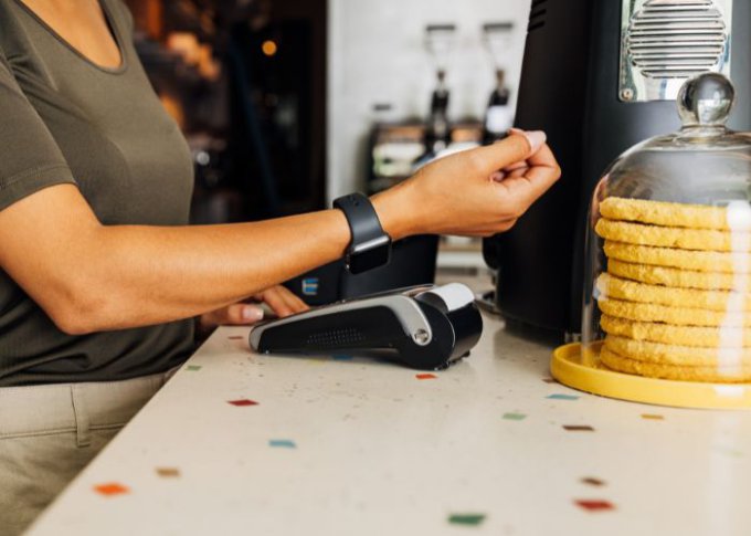 Kobieta płaci używając smartwatcha w kawiarni