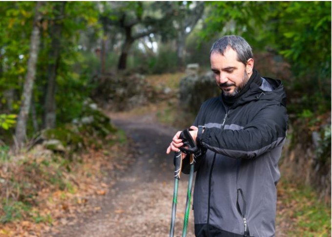 Mężczyzna w trakcie trekkingu sprawdza wiadomości na smartwatchu